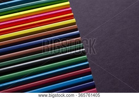 School Supplies On Dark Background. Back To School Background. Notepad And Stack Of Colorful Pencils