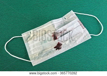 Blood Stains On A Disposable Face Mask, Close-up, Green Background.