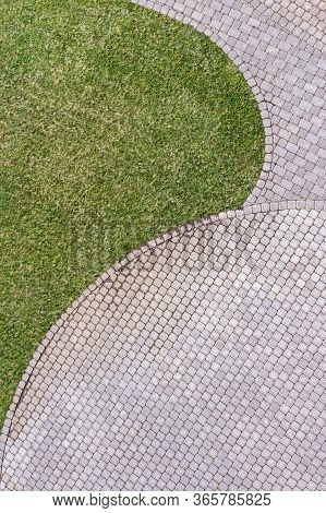 Top View Of Gray Cobblestone Pavement Footpath With Green Grass Texture Around Stones
