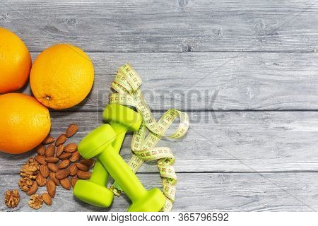 Lots Of Oranges, Dumbbells, Measuring Tape On A Wooden Textured Background. Fitness, Sports Nutritio