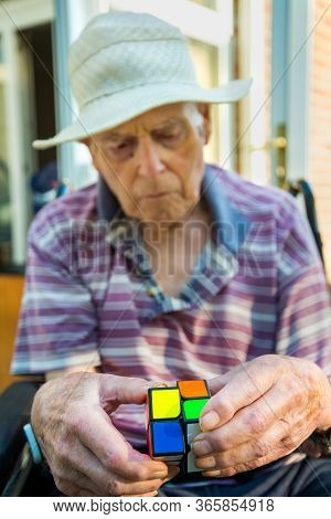 Old Man Playing A Cube Puzzle To Help With Brain Injury And Bleed.hampshire,england,united Kingdom