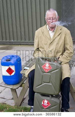 Homem fumar perto de latas de gasolina
