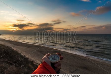 First-person View Of A Female Hand With A Compass On A Background Of A Beautiful Sea Landscape. The 