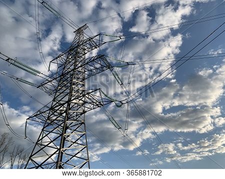 High Voltage Electric Tower Against The Blue Sky. High Steel Power Pole, Among The Forest. High Volt