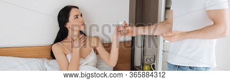 Cropped View Of Man Giving Water And Pill To Ill Woman With Sore Throat In Bed During Self Isolation