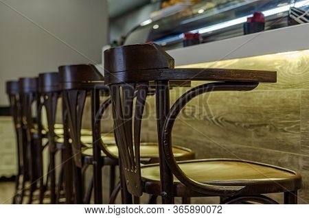 Classic Dark Wood Stools Arranged In A Row On A Bar With A Wood Texture And Lower Warm Lighting