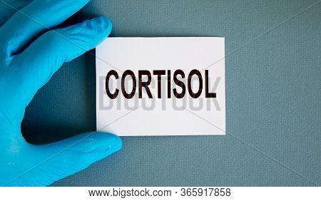 Hand In Blue Glove With White Card. Concept Word Cortisol.