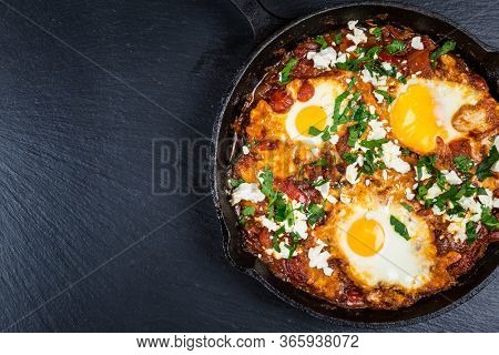 Shakshouka - Middle eastern traditional dish with poached eggs in tomato sauce with feta cheese