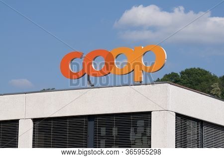 Taverne, Ticino, Switzerland - 9th May 2020 : Coop Supermarket Logo Sign Against Blue Sky Over A Sto