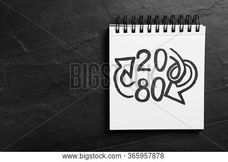 Top View Of Notebook With Numbers 20, 80 And Arrows On Black Slate Background, Space For Text. Paret