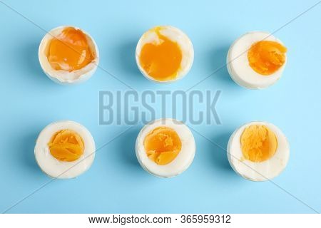 Different Readiness Stages Of Boiled Chicken Eggs On Light Blue Background, Flat Lay