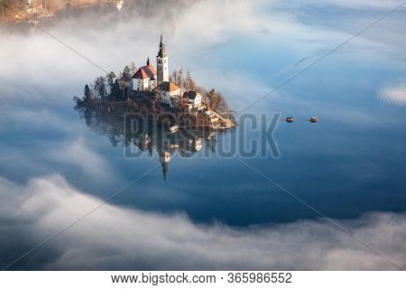 amazing panorama of Lake Bled Blejsko Jezero on a foggy morning with the Pilgrimage Church of the Assumption of Maria on a small island and Bled Castle and Julian Alps in backgroud