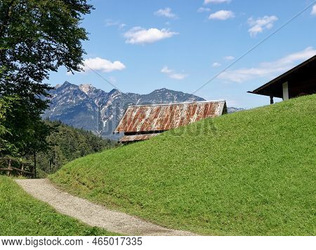 Hiking Trail In The Bavarian Alps With A View Of The Mountains And Mountain Hut In The Middle.