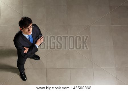 Image of young businessman in glasses arms crossed. Top view