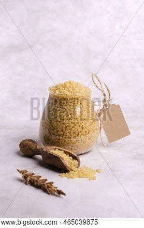 Traditional Dry Pearl Couscous In A Glass Jar On A Light Background. Selective Focus.
