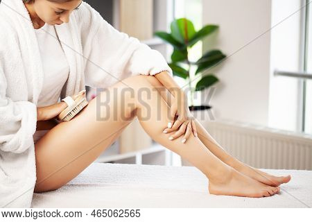Woman Holding Wooden Brush And Doing Dry Massage On Her Feet.