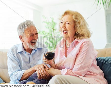 Portrait Of A Happy Senior Couple Dringking Coffee Or Tea Embracing Hugging And Having Fun At Home
