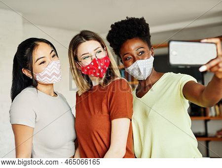 Happy Young Girls Of Diverse Ethnicity Wearing Protective Masks And Having Fun Together Taking Selfi