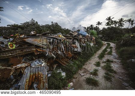 Wide-angle Shot Of An Illegal Smoking Garbage Dump Located In The Jungle Near A Dirt Road; A Landfil