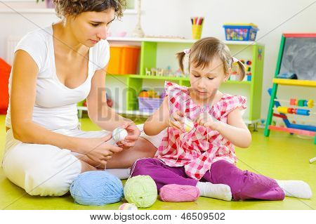Joven madre e hija pequeña decoración de huevos de Pascua