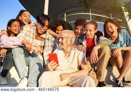 Multiracial People Having Fun Together Watching Cell Phone Screens Outdoors. Gen Z Young Students Us