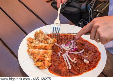 A Man Eats Beef Goulash With Czech Dumplings With A Knife And Fork.