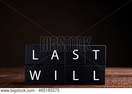 Black Cubes With Words Last Will On Wooden Table Against Dark Background