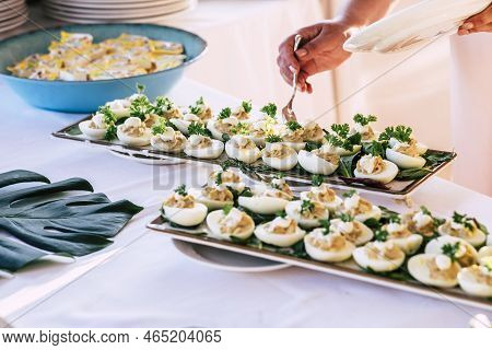Close Up Of Hand Taking Some Eggs With Vegetables And Sauce - Catering Full Of Food In A Party - Res