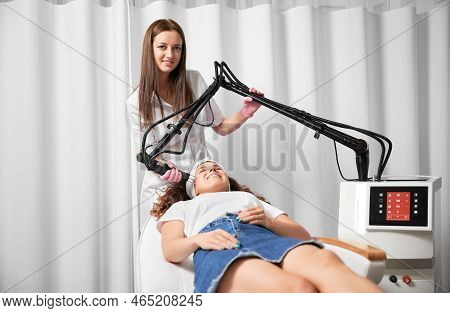 Female Doctor Cosmetologist Using Erbium Ablative Laser Machine While Performing Resurfacing Procedu