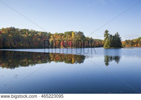 Pretty Little Blue Lake With Trees In Autumn Color And A Small Island On A Bright Morning
