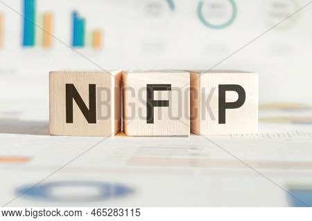 Text Nfp - Nonfarm Payrolls - On Wooden Blocks On The Background Of Financial Charts.