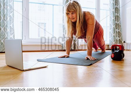 Middle-aged, Curvaceous Woman With Blond Long Hair Stands In Plank Position On Gymnastic Mat. Online