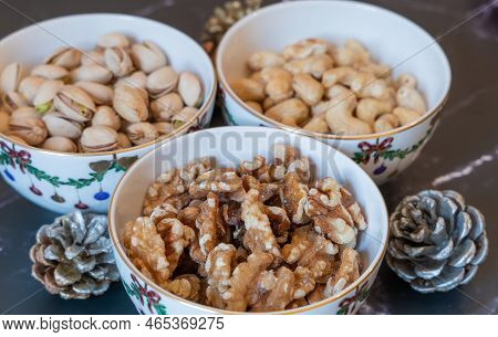 Three bowls of Christmas godies on the table. Pistachio, walnuts and cashwe nuts in Christmas bowls.