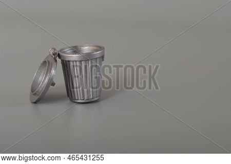 Grey Trash Can Isolated On A Grey Background. Copy Space For The Text.