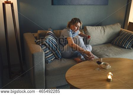 Young Happy Woman Using Nail File While Giving Herself Pedicure At Home. Female Applying Nail Polish