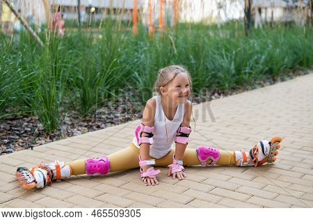 A Little Caucasian Girl Sits In A Transverse Twine Shod In Roller Skates.