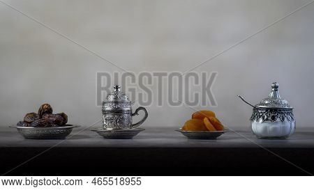Silver Coffee Cup And Sugar Jars With Dates And Dried Apricots, Light Background
