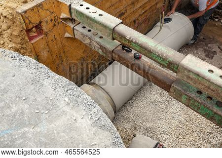 Builder Installing Big Diameter Concrete Drainage Pipe Protected By Trench Support System During Dee