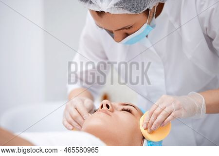 Beautician Cleanses Skin Of Beautiful Woman With A Sponge.
