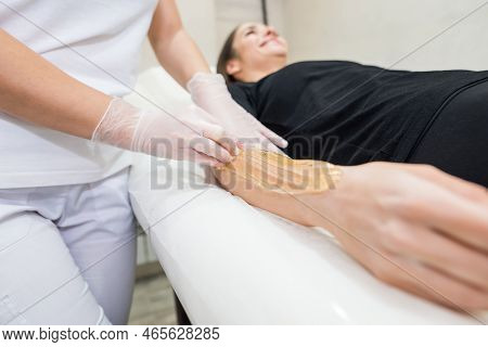 Cosmetologist Applies Sugar Paste To The Hand Of A Young Woman.depilation Of Female Hands In A Beaut