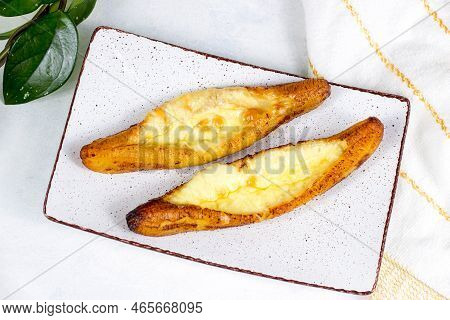 Top View Of Baked Ripe Plantains With Cheese (plantain Canoe Or Platanos Asados Con Queso) On A Plat