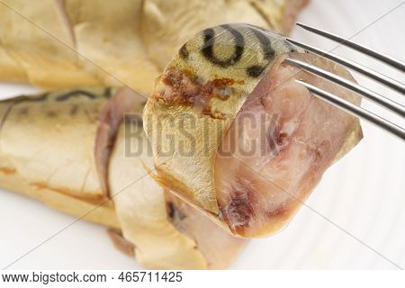 A Piece Of Smoked Fish On A Fork Against The Background Of Others. Closeup. Top View