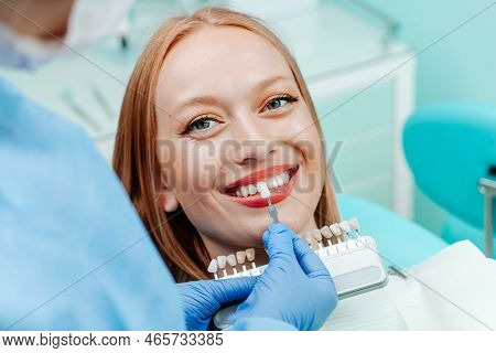Attractive Young Woman With Natural White Teeth In Dental Clinic. Hands Doctor Dentist With Teeth Co