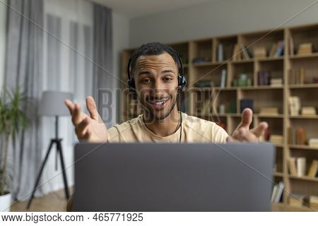 Happy Arab Man In Headphones Having Video Call On Laptop, Talking And Gesturing At Computer Webcamer