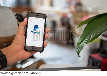 Chiang Mai, Thailand - October 15, 2022 : A Man Holding Iphone 8  On Paypal Logo Screen. Paypal Is A