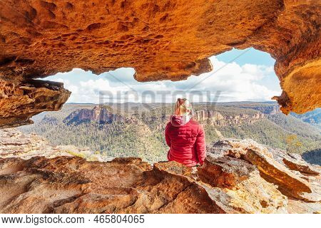 Woman Sits In A Sandstone  Cave With Spectacular Mountain Views