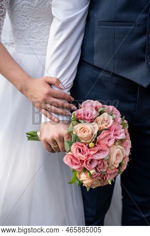 Wedding Bouquet In The Hands Of The Bride And Groom At The Ceremony. Glasses Of Champagne. Floristry