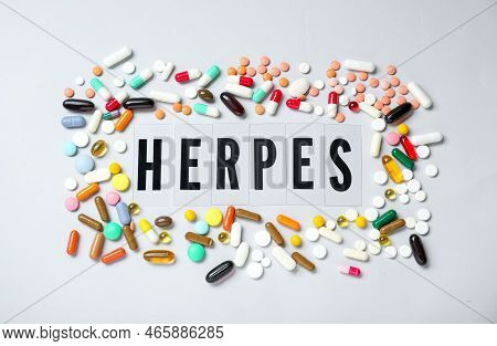 Word Herpes Surrounded By Different Pills On White Background, Top View