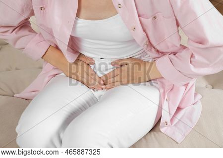 Woman Suffering From Cystitis On Sofa At Home, Closeup