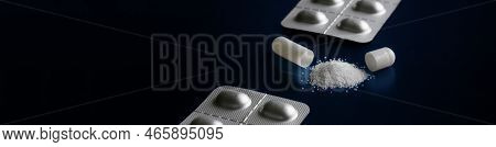 Opened White Medical Pill-capsule With Powder On A Dark Blue Textured Reflective Background Next To 